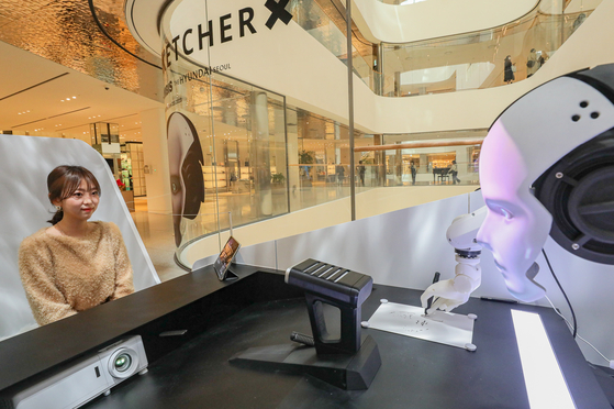 A robot draws a customer at The Hyundai Seoul in Yeouido, western Seoul, on Wednesday. The department store's "drawing robot" pop-up store on the second floor runs until March 19. [YONHAP] 