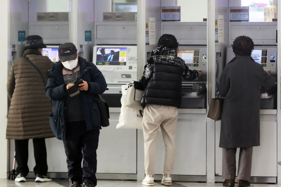 Bank customers use ATMs in Seoul on December 27. [NEWS1]