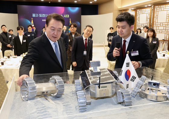 President Yoon Suk Yeol, left, looks at a model space rover at the Yongsan presidential office on Feb. 21. [YONHAP]