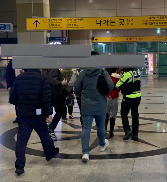 A picture that was taken by a witness posted on online of a woman being escorted by the police at Suseok station in Gyeonggi on Friday.