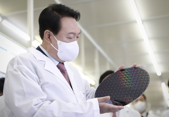President Yoon Suk Yeol examines a semiconductor wafer during a visit to KAIST in Daejeon last April. [YONHAP]