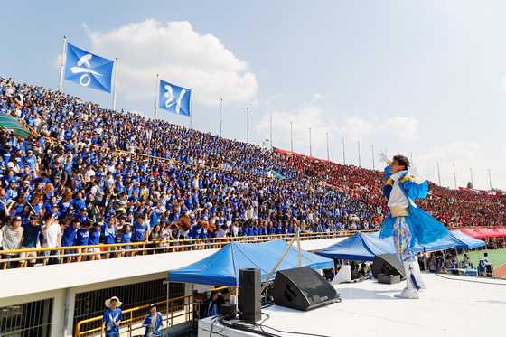 The captain of Yonsei’s iconic AKARAKA Cheering Squad performs in front of a crowd of Yonsei University students during a baseball game in 2015 against Korea University. [YONSEI UNIVERSITY]