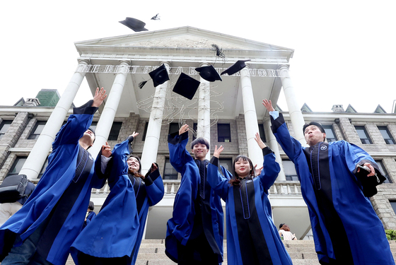 College students throw caps into the air to celebrate their graduation from Hanyang University in Seongdong District, eastern Seoul, on Thursday. Some colleges are holding regular graduation ceremonies now that social distancing measures have been eased. [YONHAP]