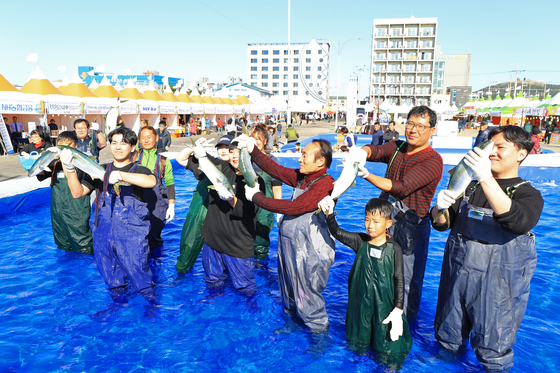 Visitors show off the yellowtail fish they caught with their bare hands at the Yellowtail Fish Festival in Moseulpo Port in November 2019. [YONHAP]