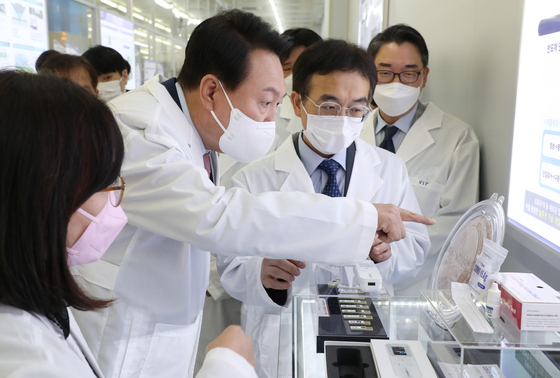 President Yoon Suk-yeol examines a semiconductor wafer at KAIST’s National NanoFab Center during a visit to the school on April 29. [YONHAP]