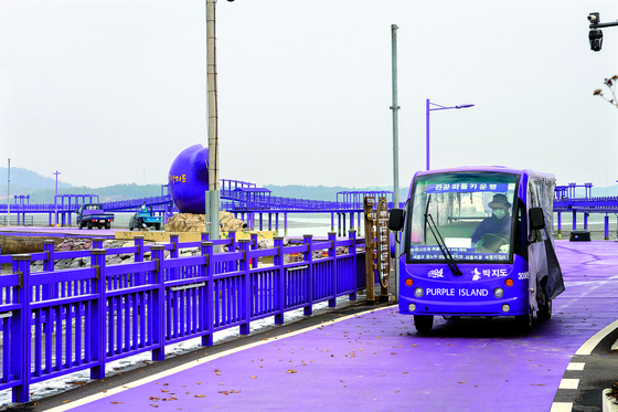 Purple Island's purple sightseeing cart is being driven on top of a purple road, surrounded by purple fences. [BAEK JONG-HYUN]