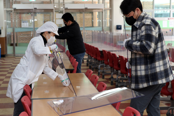 School staffers remove partitions installed at a cafeteria of Sanjeong Middle School in in the southwestern city of Gwangju ahead of the new academic year on Feb. 27. [YONHAP] 