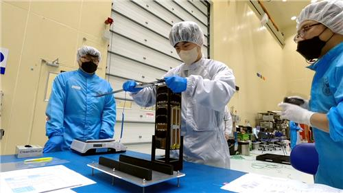 Shim Han-joon, center, a Seoul National University Ph.D. student in mechanical and aerospace engineering, loads SNUGLITE-Ⅱ, one among four CubeSats that were carried into outer space by Korea’s domestically developed rocket Nuri on June 21, before liftoff. [YONHAP]