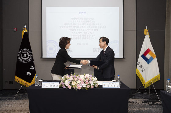 Chungnam National University President Lee, left, signs an agreement with Hanbat National University President Choi Byoung-wook on Dec. 28 in Daejeon to officially launch discussions on combining the two universities. [YONHAP]