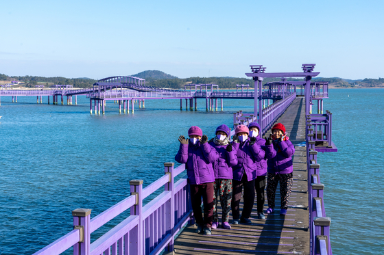 Purple Island's elderly residents, dressed in purple, greet the island's visitors on Purple Bridge. [BAEK JONG-HYUN]