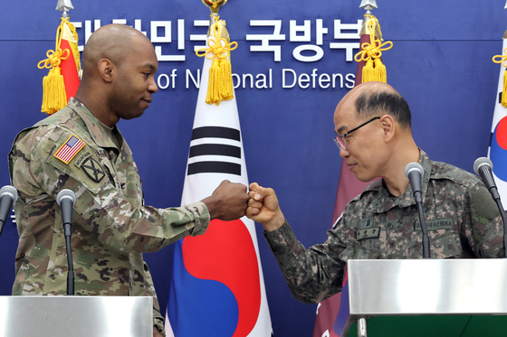 Col. Lee Sung-jun, right, spokesperson for South Korea’s Joint Chiefs of Staff, and U.S. Forces Korea spokesperson Col. Isaac L. Taylor fist-bump during a joint press conference at South Korea's Ministry of National Defense in Seoul on Friday. [YONHAP]