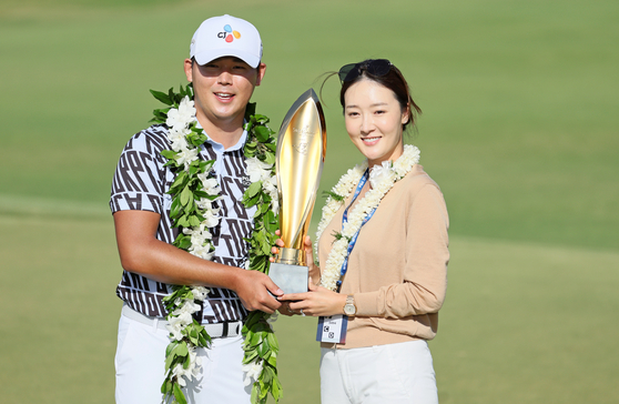 Kim Si-woo poses with his wife Oh Ji-hyun and the trophy after putting in to win on the 18th green during the final round of the Sony Open in Hawaii on Jan. 15.  [GETTY IMAGES]