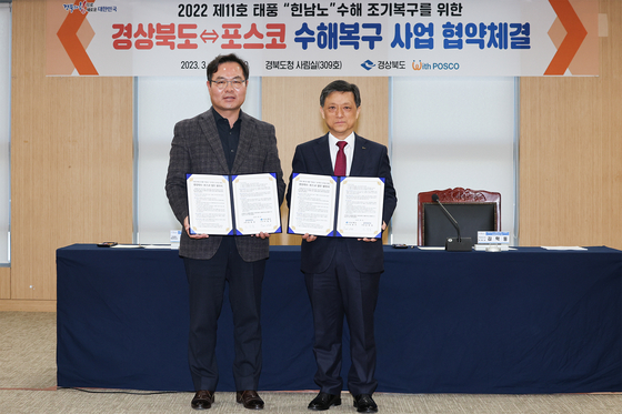 Posco Vice Chairman Kim Hag-dong, right, and Kim Hak-hong, vice governor of North Gyeongsang, take a photo after signing an agreement Monday. [POSCO]