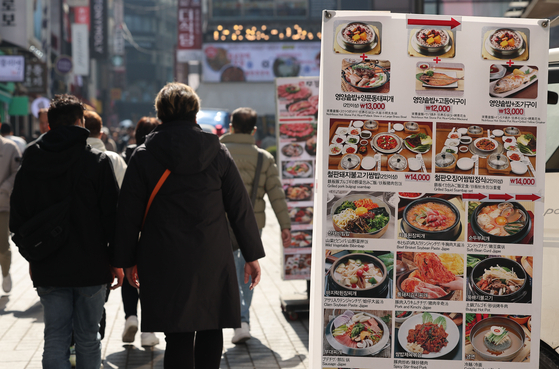 People walk past a display that shows food prices at a restaurant in central Seoul on Monday. [YONHAP]