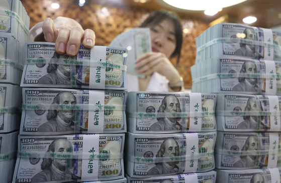 Korea’s foreign reserves fell for the first time in four months in February as a stronger dollar reduced the conversion value of holdings in other currencies, according to data from the Bank of Korea on Monday. The country’s foreign reserves were $425.29 billion at the end of February, down $4.68 billion from the previous month. The photo above shows employees organizing the dollar bills at Hana Bank in Jung District, central Seoul, on Monday. [YONHAP] 