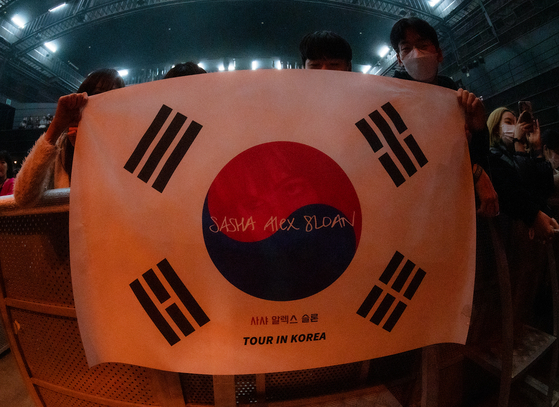 Fans hold up a Korean flag decorated with Sasha Alex Sloan's name during the singer's first concert in Korea held on Monday at the Yes24 Live Hall music venue in eastern Seoul as a part of her ″I Blame The World″ Asia tour. [LIVE NATION KOREA]