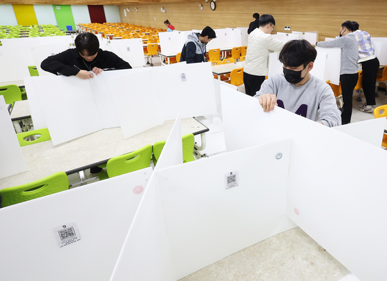 Teaching staff at Samil Technical High School in Suwon, Gyeonggi, on Feb. 27 remove partitions installed at cafeterias as a safety measure to prevent Covid-19, ahead of the new academic semester. [YONHAP] 