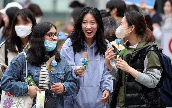 Students smile after receiving roses in front of Ewha Womans University in Seodaemun District, western Seoul, gifted by non-profit women's rights group Korea Women's Hot-Line in commemoration of International Women's Day on Wednesday. The United Nations officially designated March 8 as International Women's Day in 1977. [NEWS1] 