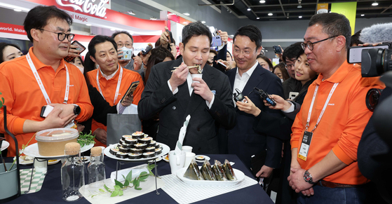 Shinsegae Group Vice Chairman Chung Yong-jin tastes a sample dish at a food contest exhibiting dishes made by Emart 24 convenience store owners in Seocho District, southern Seoul, on Wednesday. The top three dishes of the contest, the Delicious Recipe Contest, will be sold in Emart 24 stores as actual products. [YONHAP]