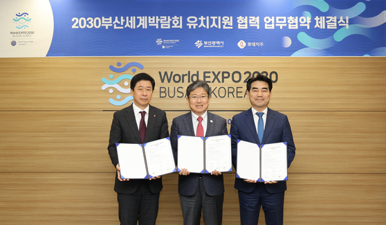 Lotte signs a memorandum of understanding with the World Expo 2030 Bid Committee and Busan Metropolitan City to help promote the city on Wednesday. From left, Lotte Holdings Communication Director Lee Gap, Bid Committee's Busan Secretary General Yoon Sang-jick and Busan Vice Mayor for Economic Affairs Lee Seong-kweun pose for the photo after signing the deal. [LOTTE]