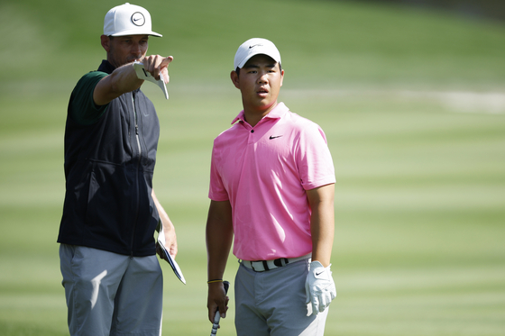 Tom Kim, right, talks with his caddie Joe Skovron as he looks on during a practice round prior to The Players Championship on The Players Stadium Course at TPC Sawgrass on Tuesday in Ponte Vedra Beach, Florida. [GETTY IMAGES]