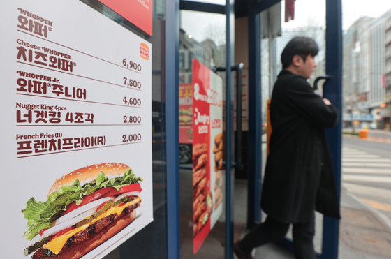 A menu pamplet is posted at a Burger King store in Seoul on Wednesday. Burger King will raise prices for some of its menu items from Friday, announced the global burger company on Wednesday. The prices of 32 burgers, 15 snacks and drinks will be upped by 2 percent on average. Its trademark Whopper will be sold at 7,100 ($5.40) won from Friday, up 200 won. [YONHAP]