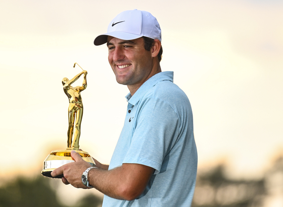 Scottie Scheffler smiles with the tournament trophy after his five stroke victory in the final round of The Players Championship on the Stadium Course at TPC Sawgrass on Sunday in Ponte Vedra Beach, Florida. [GETTY IMAGES] 