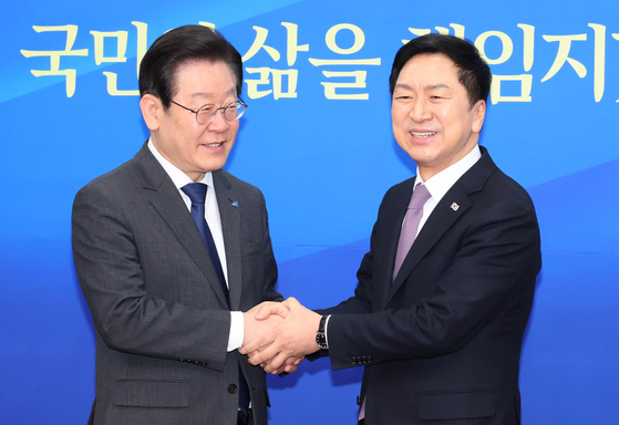 Democratic Party Chairman Lee Jae-myung, left, shakes hands with the newly-elected chairman of the People Power Party, Kim Gi-hyeon, on Wednesday at the National Assembly in Yeouido, western Seoul. [YONHAP]