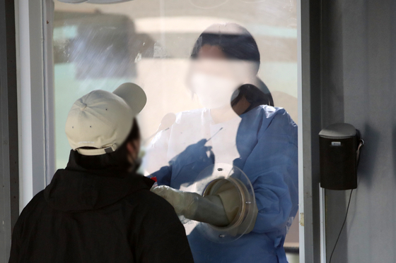 A medical staff takes a sample at a Covid-19 testing center in Yongsan District, central Seoul, on Monday. [NEWS1]