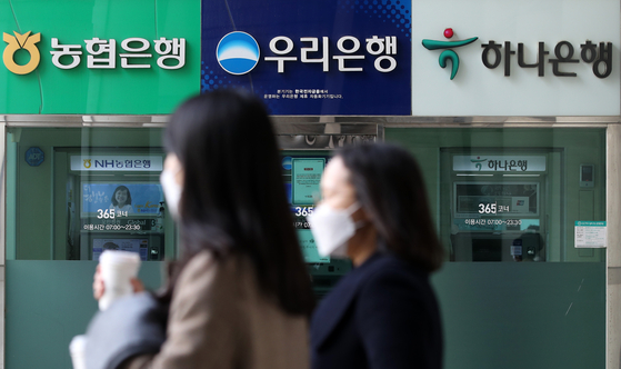 People walk past automated teller machines in Seoul. [NEWS1]