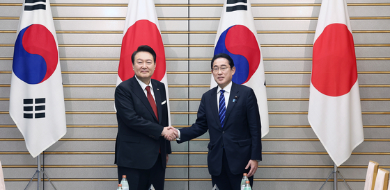 Korean President Yoon Suk Yeol, left, and Japanese Prime Minister Fumio Kishida shake hands during their bilateral summit in Tokyo Thursday. [JOINT PRESS CORPS]