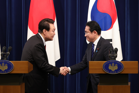 Korean President Yoon Suk Yeol, left, and Japanese Prime Minister Fumio Kishida shake hands at a press conference held after their bilateral summit in Tokyo Thursday. It was the first time a Korean president made a visit to Japan for a bilateral summit in 12 years. [JOINT PRESS CORPS]