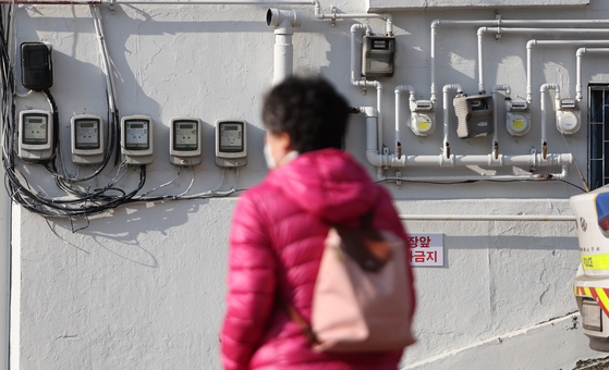A person stands in front of electricity and gas meters of a building in Seoul on March 6. [YONHAP]