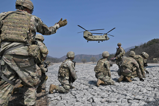 U.S. soldiers take a position as a U.S. Army CH-47 Chinook helicopter prepares to land during a field artillery battalion gun raid drill at a military training field in Pocheon on Sunday, as part of the Freedom Shield joint military exercise. [AFP/YONHAP]