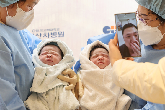 A father meets his twin babies through a video call. [YONHAP]