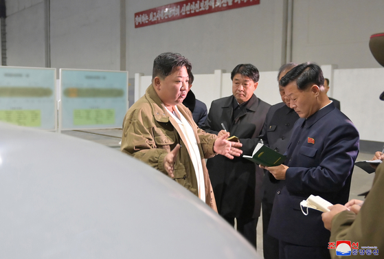 The blurred-out schematics of the ″underwater nuclear attack drone″ tested by Pyongyang between March 21 and 23 are visible behind leader Kim Jong-un issuing guidance to North Korean officials in this photo released by the Korean Central News Agency. [YONHAP]