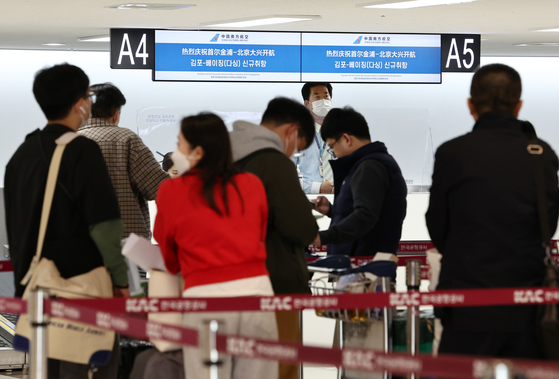 Travelers to China wait in line at Gimpo International Airport on Sunday. [YONHAP]