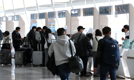 People stand in front of travel agency counters in Incheon International Airport on March 18. [NEWS1]