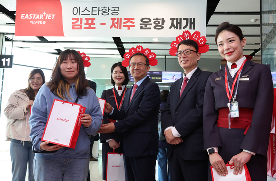 Eastar Jet CEO Cho Joong-seok, fourth from left, and company officials pose for a photo with a passenger who won a promotional event at Gimpo International Airport on Sunday. [YONHAP]