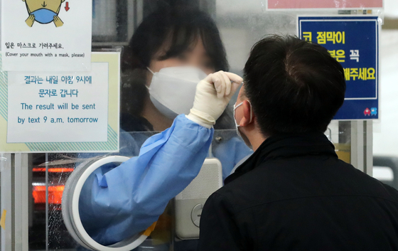 A staff member takes a PCR test sample at a Covid-19 testing center in Songpa District, southern Seoul, on Tuesday. [NEWS1]