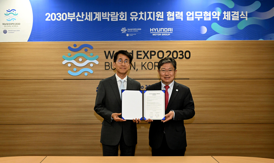 Kim Dong-wook, left, executive vice president at Hyundai Motor, and Yoon Sang-jik, secretary general of the bidding committee, pose for a photo during a signing ceremony held in central Seoul, Tuesday. [HYUNDAI MOTOR]