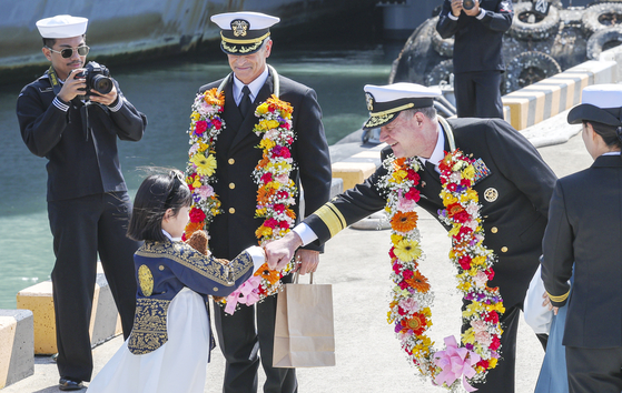 Rear Adm. Christopher Sweeney, commander of the U.S. Navy's Carrier Strike Group 11, is greeted by a child dressed in traditional hanbok in Busan after the arrival of USS Nimitz on Tuesday. [YONHAP]
