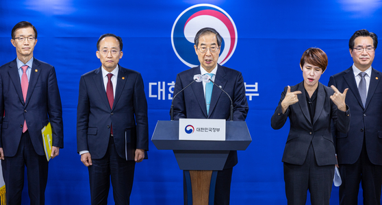 Prime Minister Han Duck-soo, center, announces his plan to advise President Yoon Suk Yeol to veto the reform bill on the mandatory purchase of oversupplied rice, in Seoul on Wednesday. [YONHAP]