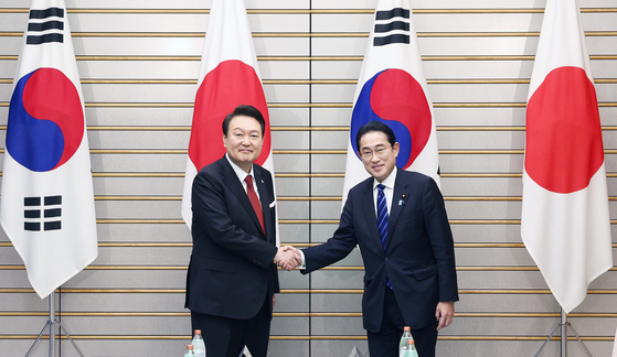 Korean President Yoon Suk Yeol, left, and Japanese Prime Minister Fumio Kishida, right, shake hands at their bilateral summit in Tokyo on March 16. [JOINT PRESS CORPS] 