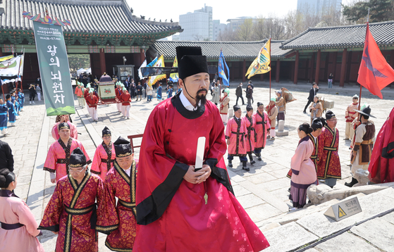 Boseong County Governor Kim Chul-woo, in red, participates in a re-enactment of the offering of powdered Boseong Noewon tea to the king during the Goryeo Dynasty (918-1392) at Gyeonghui Palace in Seoul on Thursday. South Jeolla’s Boseong World Tea Expo runs from April 29 to May 5. Boseong is known for its tea farms. [YONHAP]