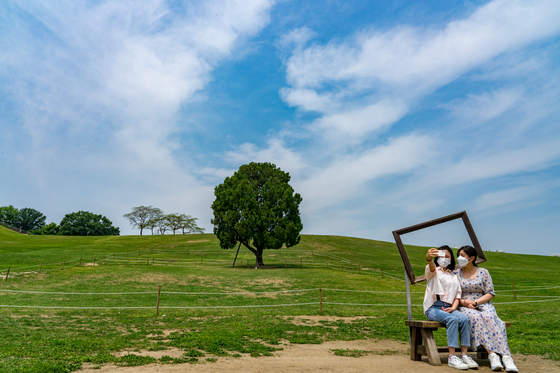 Visitors take pictures with the Lone Tree in Olympic Park. [BAEK JONG-HYUN]