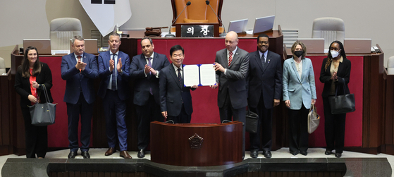 President of the BIE's Administration and Budget Committee, Patrick Specht, center right, holds up the Korean National Assembly’s resolution that promises the Korean legislative body’s full commitment in supporting the successful hosting of the World Expo 2030 if Busan is picked, with National Assembly Speaker Kim Jin-pyo in Yeouido, Seoul, on Monday. [YONHAP] 