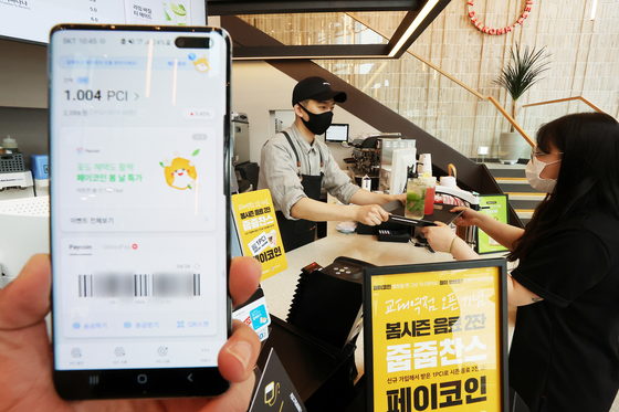 A model demonstrates the use of Paycoin to buy beverages at a cafe in southern Seoul in April 2021. [NEWS1]