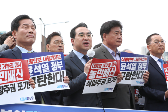 Democratic Party floor leader Park Hong-keun, center, speaks at a rally to protest the president’s veto of an amendment to the Grain Management Act which requires the government to purchase surplus rice in front of the Yongsan presidential office in central Seoul Tuesday. Lawmakers hold up signs reading “betrayal of farmers.” [NEWS1]