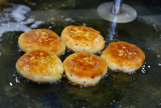 Hotteok, which is Korean fried bread with melted brown sugar, is being fried at a street cart in Busan [JOONGANG ILBO]